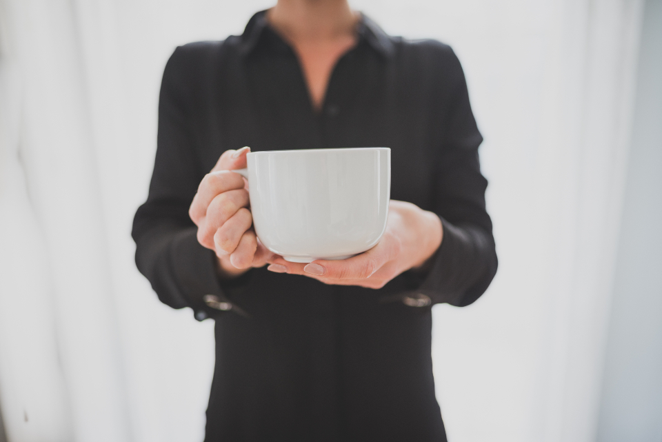 マグカップを両手で持ち、ひと息つく女性